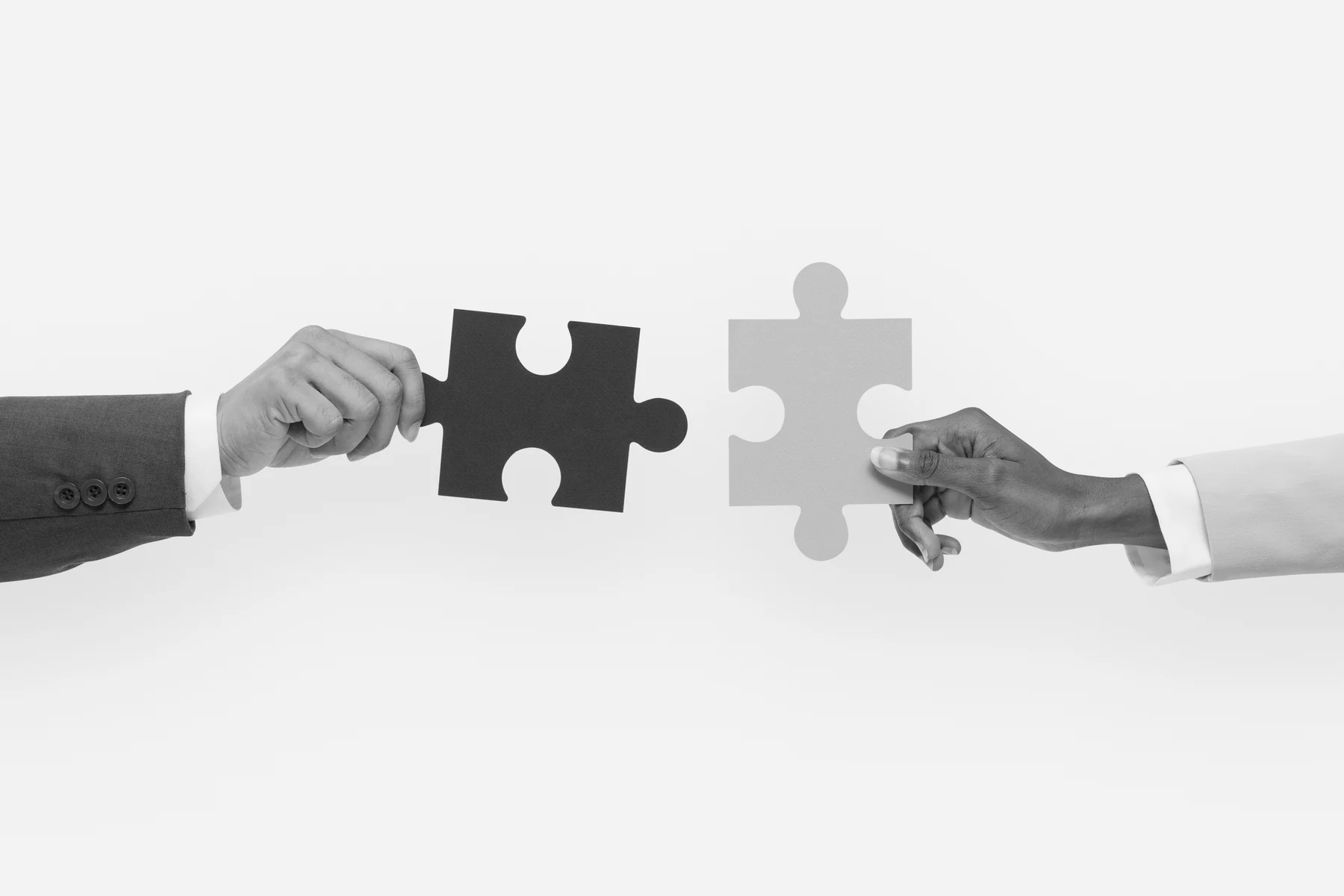 Two hands bringing puzzle pieces together